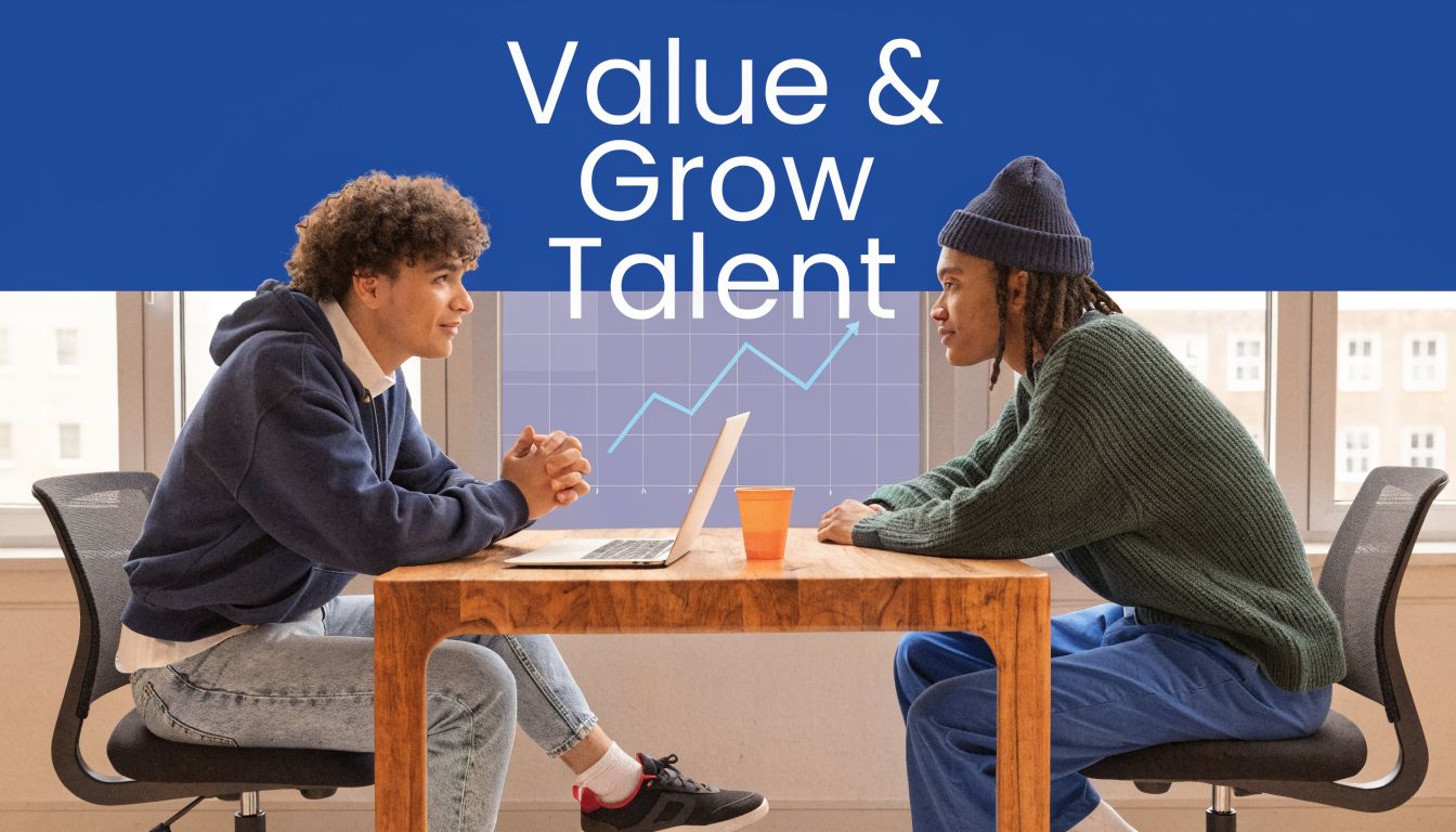 Two young professionals sitting at a table with a laptop, discussing career growth in an office setting.