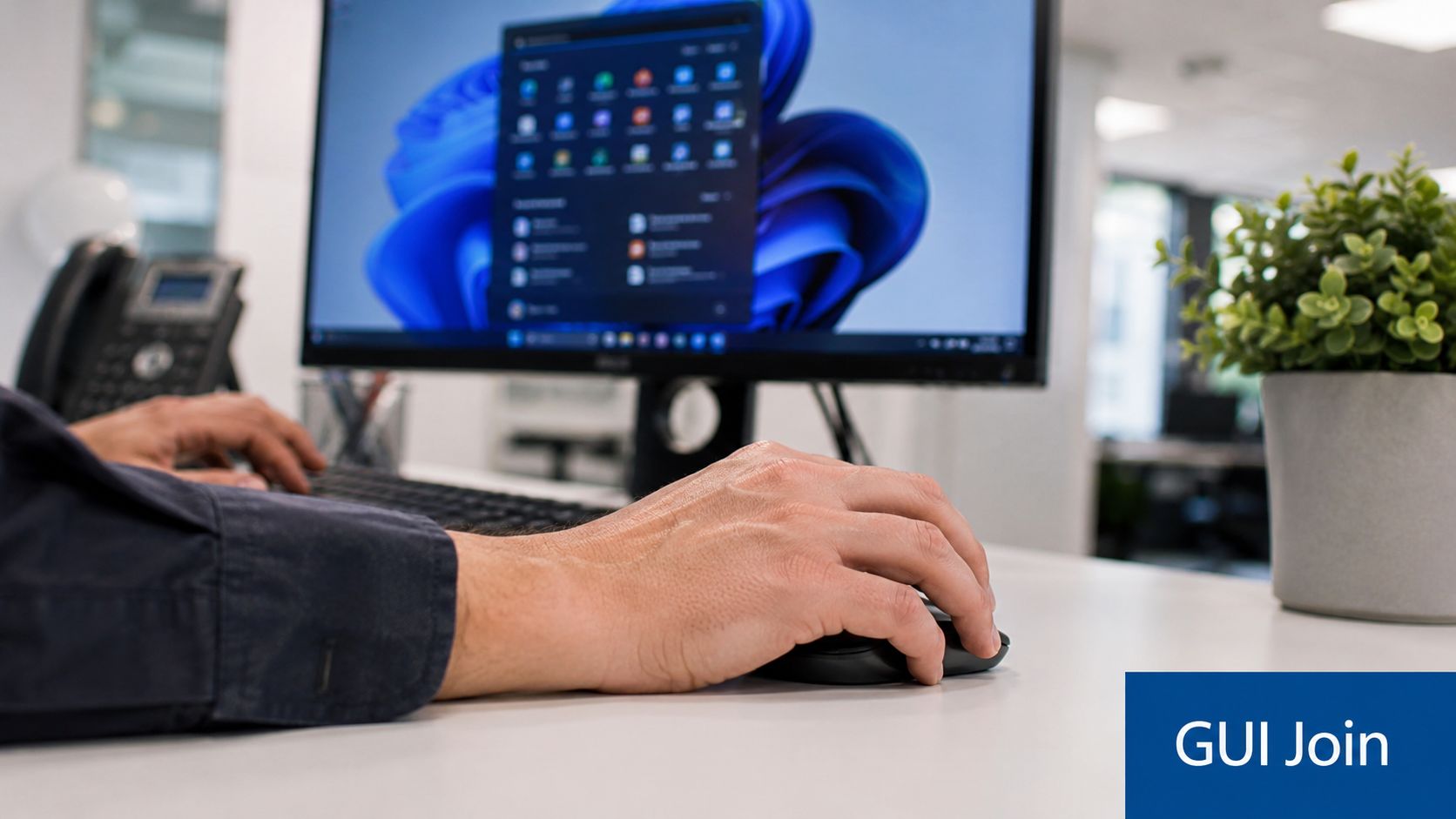 A person working at a desk using a computer with Windows 11 interface displayed on the screen.
